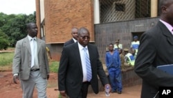Elton Mangoma, center, Zimbabwe's Minster of Energy and Power Development outside the magistrates courts, accompanied by two unidentified police detectives in Harare, March, 11, 2011
