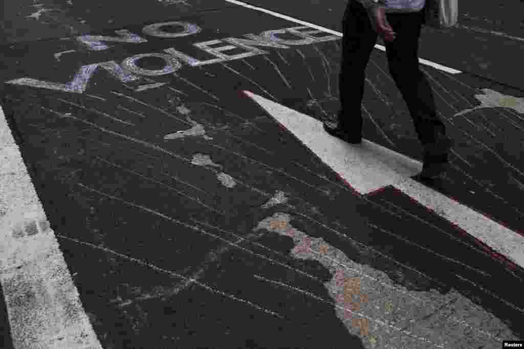 Um manifestante passa pelo slogan &quot;Violância Não&quot; escrito no chão da rua principal em Mongkok, que foi ocupada pelos manifestantes, em&nbsp; Hong Kong, Set. 30, 2014. 