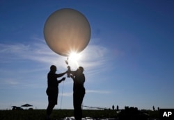 Mike Newchurch, left, professor of atmospheric chemistry at the University of Alabama in Huntsville, and graduate student Paula Tucker prepare a weather balloon before releasing it to perform research during the solar eclipse Aug. 21, 2017, on the Orchard Dale historical farm near Hopkinsville, Ky.