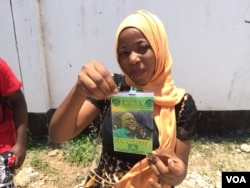 CCM supporter shows her candidate's photo on a campaign badge in Dar es Salaam, Oct. 24, 2015. (Jill Craig/VOA)