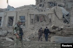 FILE - Afghan security forces and NATO troops investigate at the site of an explosion near the German consulate in Mazar-i-Sharif, Afghanistan, Nov. 11, 2016.