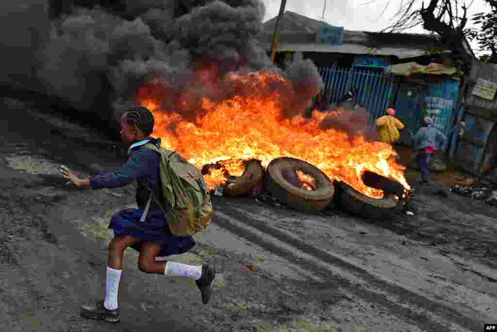 Seorang siswi sekolah berlari di antara ban-ban yang dibakar di distrik Kibera, Nairobi, Kenya, pada saat aksi demonstrasi pendukung oposisi menuntut pergantian kepemimpinan di sana.