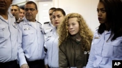 FILE - Ahed Tamimi, a 17-year-old from the West Bank village of Nebi Saleh, is brought to a courtroom inside Ofer military prison near Jerusalem, Dec. 28, 2017. 