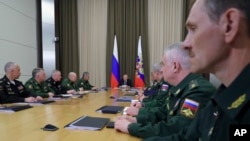 Russian President Vladimir Putin, background center, leads a meeting with the top military brass in the Bocharov Ruchei residence in the Black Sea resort of Sochi, Russia, May 15, 2018. Putin says the new weapons presented this year will ensure Russia's security for decades to come.