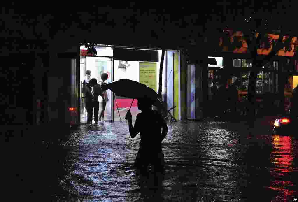D&acirc;n ch&uacute;ng đội mưa đi tr&ecirc;n một con đường ngập lụt ở Bắc Kinh, 21/7/2012.