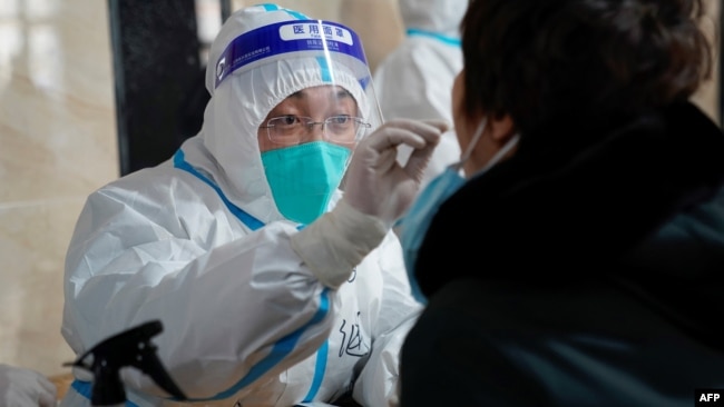 中国哈尔滨一位医疗人员在进行新冠检测采样 （法新社 2021年1月14日）