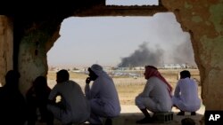 FILE - Jordanian residents of Jabir village watch aid deliveries to Syrians fleeing government offensives in the south as smoke from an unknown fire rises, July 3, 2018. 