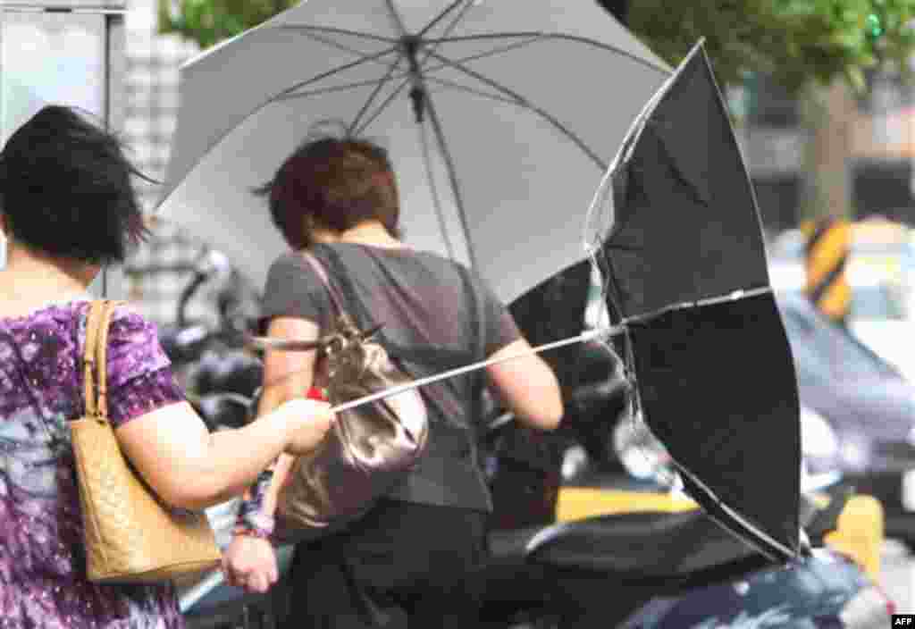 A woman with an umbrella is caught by powerful gusts of wind generated by typhoon Nanmadol in Taipei, Taiwan, Monday, Aug. 29, 2011. Typhoon Nanmadol has slammed into Taiwan, closing schools, workplaces and government offices. It has dumped more than 19 i