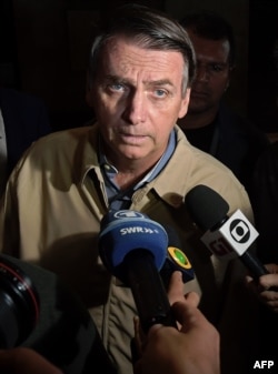Brazilian far-right presidential candidate Jair Bolsonaro speaks to the press during a visit to the Federal Police station in Rio de Janeiro, Oct. 17, 2018.