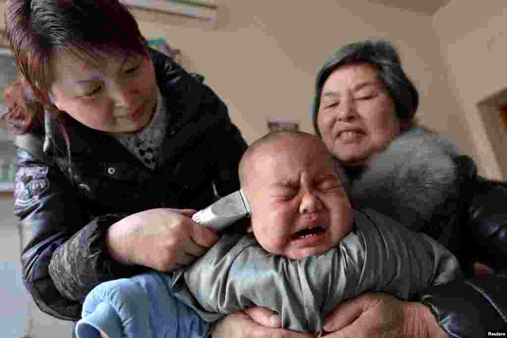 Một đứa trẻ khóc trong khi được hớt tóc trong ngày lễ Long Đài Đầu (rồng ngẩng đầu), ngày thứ hai của tháng thứ hai âm lịch, ở huyện Bảo Khang, tỉnh Hồ Bắc, Trung Quốc.