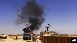 FILE - Militants from the al-Qaida-inspired Islamic State, formerly known as the Islamic State in Iraq and the Levant (ISIL), raising their flag at an army base in Ninevah Province, Iraq.