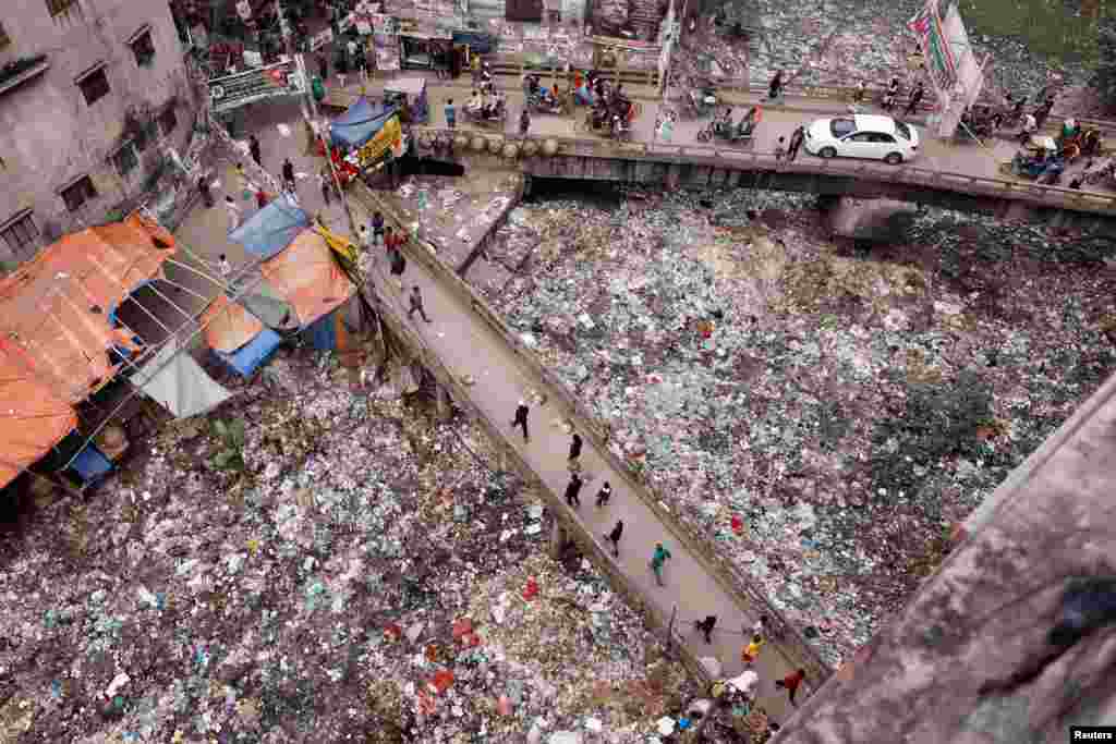 People walk along a bridge over a polluted area in Dhaka, Bangladesh.