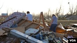 Warga berjalan di antara reruntuhan rumahnya setelah terjadinya tornado di Harrisburg, Illinois. Tornado menghantam beberapa kawasan di Amerika tenggara.