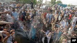 FILE - People cool off in a spray from a broken water pipe during a heat wave, in Karachi, Pakistan, May 31, 2017. 