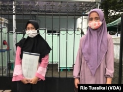 Gunita Sri (kiri) dan sepupunya yang juga relawan Riani Wulandari (kanan) berdiri dengan jarak fisik usai mengikuti penyuntikkan vaksin dalam uji klinis tahap 3 di Puskesmas Dago, Bandung, Jumat (14/8) siang. (VOA/Rio Tuasikal)