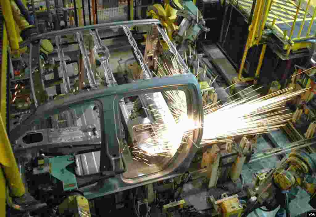 Sparks fly as a robot helps to assemble a vehicle in a GM factory. (Steve L. Herman/VOA)