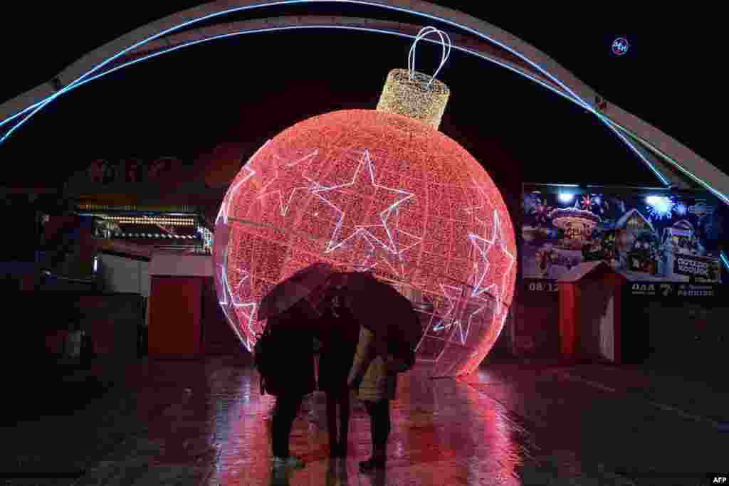 People stand in the entrance of International Fair, decorated by a giant Christmas ball in Thessaloniki, Greece.