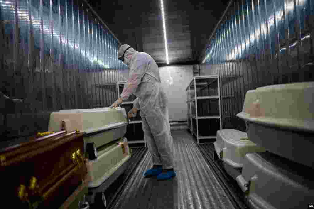 An AVBOB mortuary employee wearing full PPE checks coffins containing the remains of COVID-19 victims in a refrigerated container in Johannesburg, South Africa.