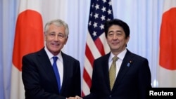 Menhan AS Chuck Hagel (kiri) dan PM Jepang Shinzo Abe berjabat tangan sebelum memulai pertemuan di Tokyo (5/4).