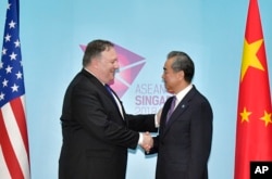 U.S. Secretary of State Mike Pompeo (L) and China's Foreign Minister Wang Yi shake hands ahead of a bilateral meeting on the sidelines of the 51st ASEAN Foreign Ministers Meeting in Singapore, Aug. 3, 2018.