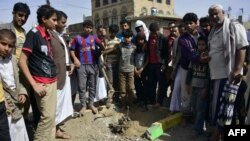 Yemenis gather at the site of a bomb explosion that targeted an army troop vehicle on its way to man a checkpoint on a street leading to two western embassies, May 9, 2014, in Sana'a. 