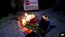 Palestinians burn a poster of the U.S. President Donald Trump during a protest in Bethlehem, West Bank, Dec. 6, 2017. Defying dire, worldwide warnings, President Donald Trump on Wednesday broke with decades of U.S. and international policy by recognizing Jerusalem as Israel's capital.