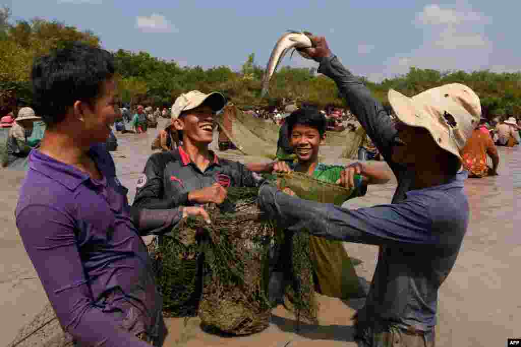 A man raises a snake fish up during the annual fish-catching ceremony at Choam Krovean commune in Tboung Khmum province, Cambodia.