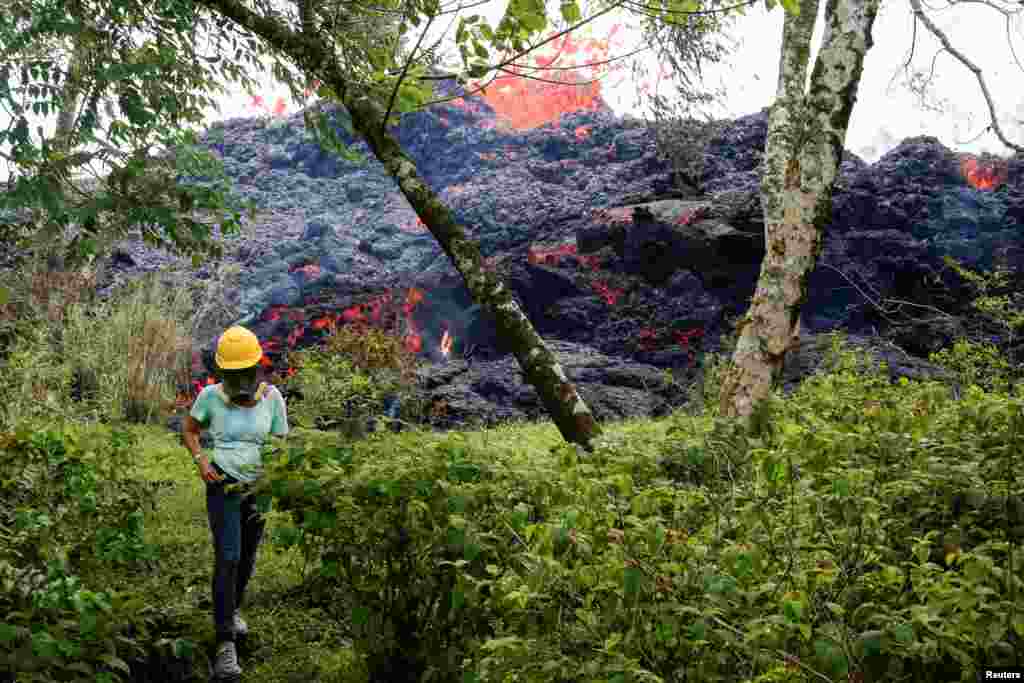 An onlooker watches as lava erupts from a fissure east of the Leilani Estates subdivision during ongoing eruptions of the Kilauea Volcano, May 12, 2018.