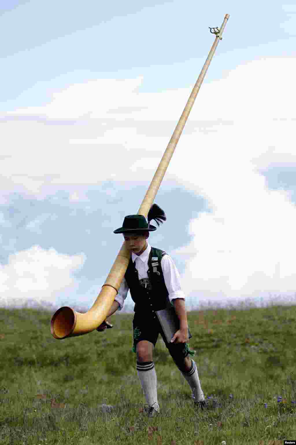 A young Alphorn blower carries his Alphorn before performing an ensemble piece on the last day of the International Alphorn Festival on Lac de Tracouet near the village of Nendaz, Switzerland.