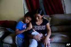 Aura Gaspar sits with her two-week old baby Ashley, and her son, Isaac, 5, in their home, dark due to a power failure from Hurricane Irma, in Immokalee, Florida, Sept. 12, 2017.