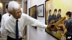 In this photo taken July 12, 2007, Khmer Rouge death camp survivor Vann Nath describes his painting during an exhibition in Phnom Penh. 