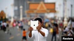 FILE - Lary, 27, takes a picture with his tablet in Phnom Penh.