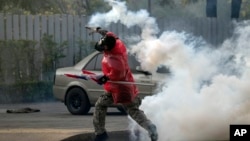 26일 태국 방콕의 반정부 시위 현장에서, 한 시위대가 경찰이 발사한 최루탄을 다시 경찰울 향해 던지고 있다.