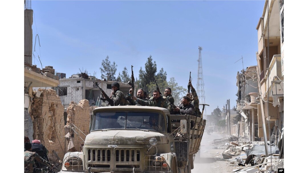 FILE - Syrian soldiers celebrate their victory against the Islamic State group in Qaryatain, Syria, April 4, 2016.