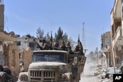 FILE - Syrian soldiers celebrate their victory against the Islamic State group in Qaryatain, Syria, April 4, 2016.