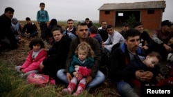FILE - Syrian refugees who crossed the Evros river, the natural border between Greece and Turkey, rest on a field as they wait for the police to arrive and transfer them to a first reception center, near the village of Nea Vyssa, Greece, May 2, 2018.