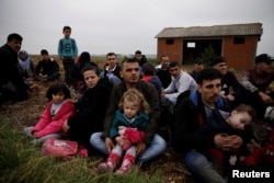 FILE - Syrian refugees who crossed the Evros river, the natural border between Greece and Turkey, rest on a field as they wait for the police to arrive and transfer them to a first reception center, near the village of Nea Vyssa, Greece, May 2, 2018.