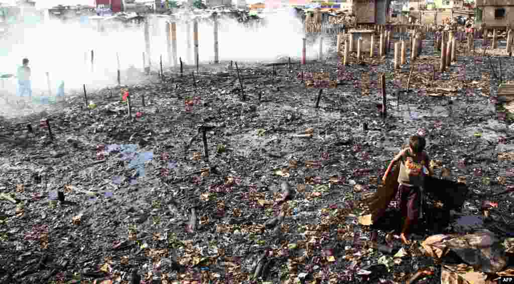 Children scavenge among twisted metal and corrugated iron sheets in the ruins of a slum after a fire in Davao City. A huge night fire destroyed more than a thousand homes in a slum in the Philippines&#39; largest southern city, sending residents running for their lives, officials said.