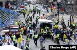 FILE - Medical workers aid injured people at the finish line of the 2013 Boston Marathon following an explosion, April 15, 2013.