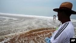 A Chinese man watches heavy seas by the coastline in Qingdao, in eastern China's Shandong province on Aug. 8, 2011, as typhoon Muifa traveled north, drenching the eastern province of Shandong.