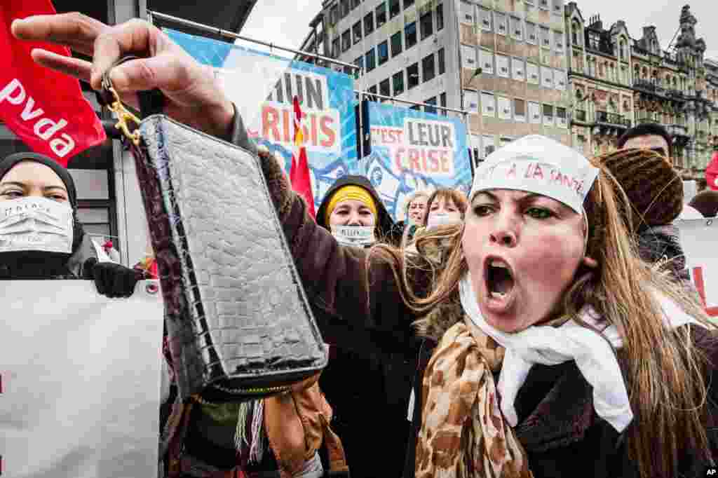 A worker shouts and shows her wallet as she demonstrates together with tens of thousands of workers to protest against austerity measures that have affected their income during the financial crisis and to demand labor-boosting initiatives, in Brussels, Belgium.