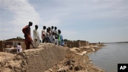 FILE: Residents stand on a house destroyed by floods in the village of Hadeja, near Dutse in northern Nigeria. Taken 9.27.2010