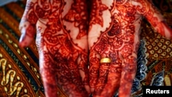 FILE - A bride shows her decorated hands and an engagement ring as she waits for her future husband to arrive for their wedding in Banda Aceh December 9, 2012.