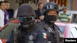 FILE - Mexican federal police officers are seen standing guard during a raid.