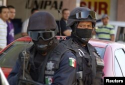 FILE - Mexican federal police officers are seen standing guard during a raid.