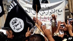 FILE - Demonstrators wave al-Qaida flags in front of the provincial government headquarters in Mosul, Iraq.