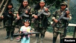 En esta foto confircada por la policía colombiana, guerrilleras de las FARC posan con sus armas junto a una niña. Las menores son obligadas a brindar favores sexuales a sus 'superiores', señalan declaraciones. 