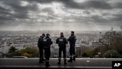 FILE - French police officers stand guard near the church of Sacre Coeur, on top of Montmartre hill, in Paris, Nov. 18, 2015, days after coordinated terrorist attacks killed 130 people in the French capital. 