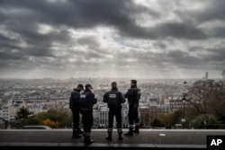 Paris is seen as French police officers stand on guard near the church of Sacre Coeur, on top of the Montmartre hill, in Paris, Nov. 18, 2015.