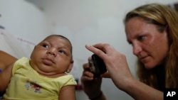 Pediatrician Alexia Harrist from the United States' Centers for Disease Control and Prevention (CDC) takes a picture of 3-month-old Shayde Henrique who was born with microcephaly, after examining him in Joao Pessoa, Brazil, Tuesday, Feb. 23, 2016. In its